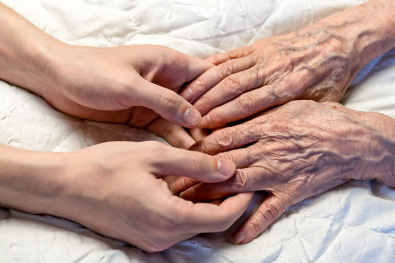 a view of a younger person's hands holding an older person's hands